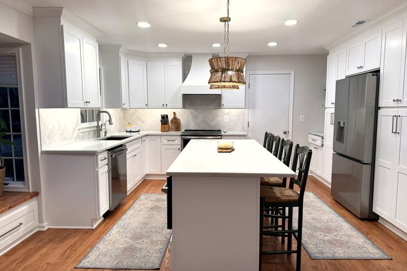 Remodeled kitchen in Millersville, MD with a white quartz island, herringbone tile backsplash, range hood and floor-to-ceiling pantry cabinets