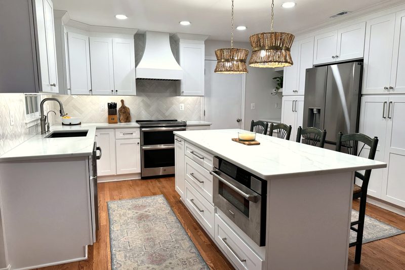 Remodeled kitchen with white shaker cabinets, a quartz island with a built-in microwave drawer, and woven pendant lights